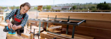 A woman using a cordless sander outdoors.