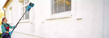 A woman using a drywall sander to sand and renovate walls.